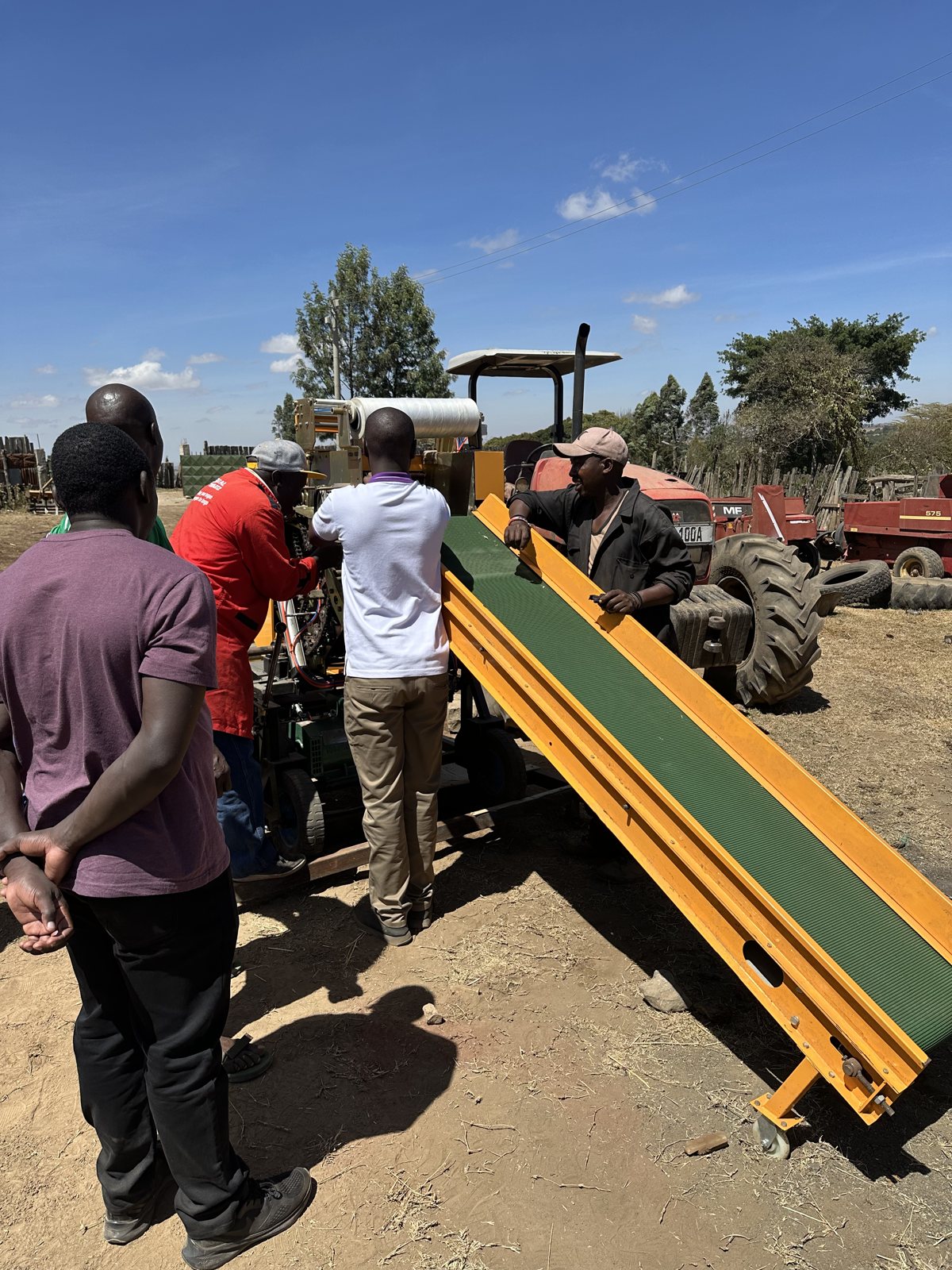 Timothy's team lifting the infeed conveyor into position on the baler wrapper in the farm yard