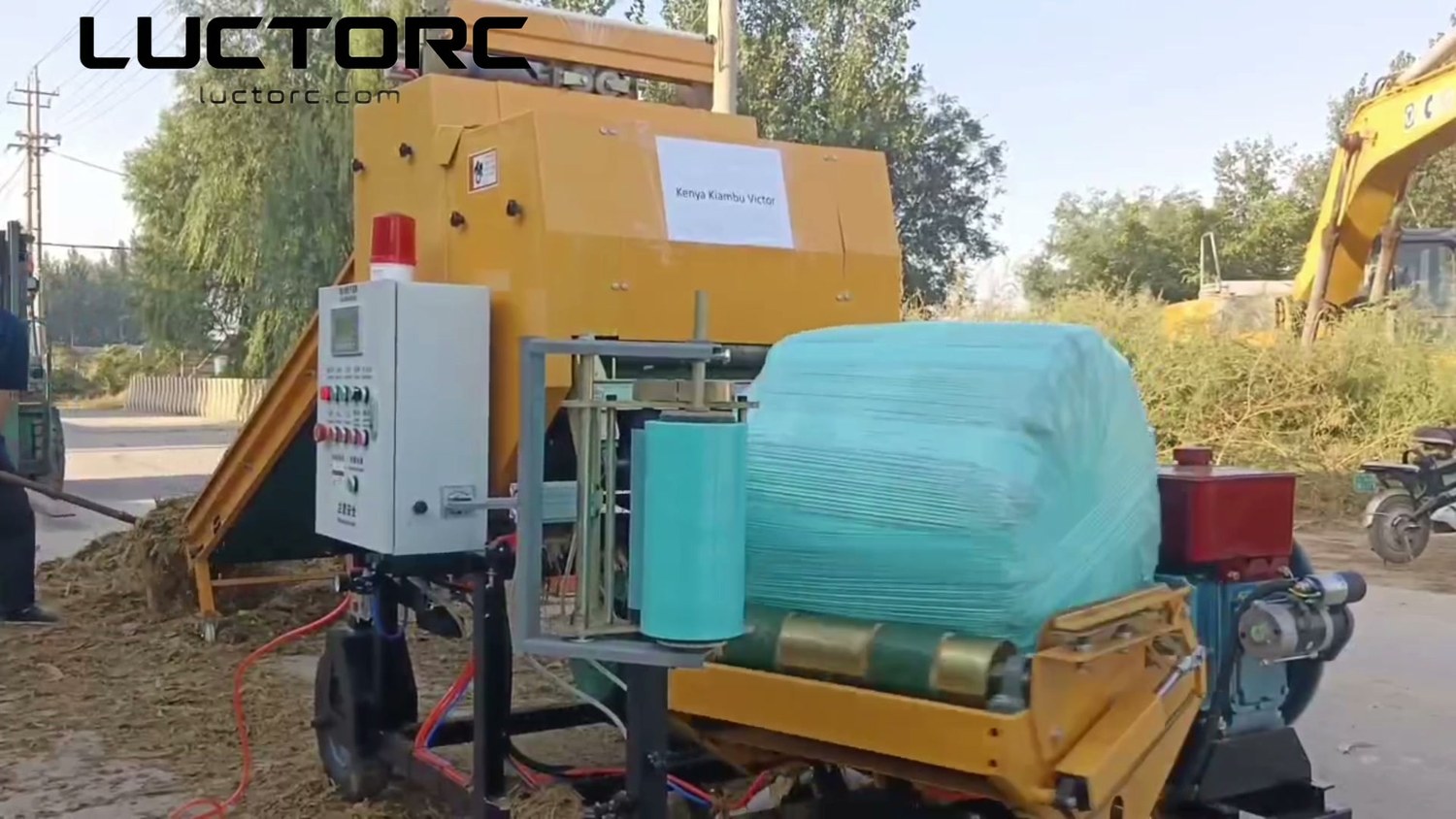 Victor's tagged LUCTORC baler wrapper mid-cycle, film wrapping around a freshly pressed bale